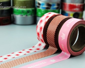 May include: Three rolls of washi tape with different patterns. The first roll has a white background with red starbursts, the second roll has a brown background with a white checkered pattern, and the third roll has a pink background with a white crown and the word "princess" printed on it.