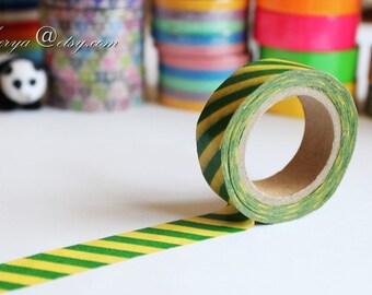 May include: A roll of green and yellow striped washi tape. The tape is partially unrolled, showing the pattern. The tape is on a white surface.