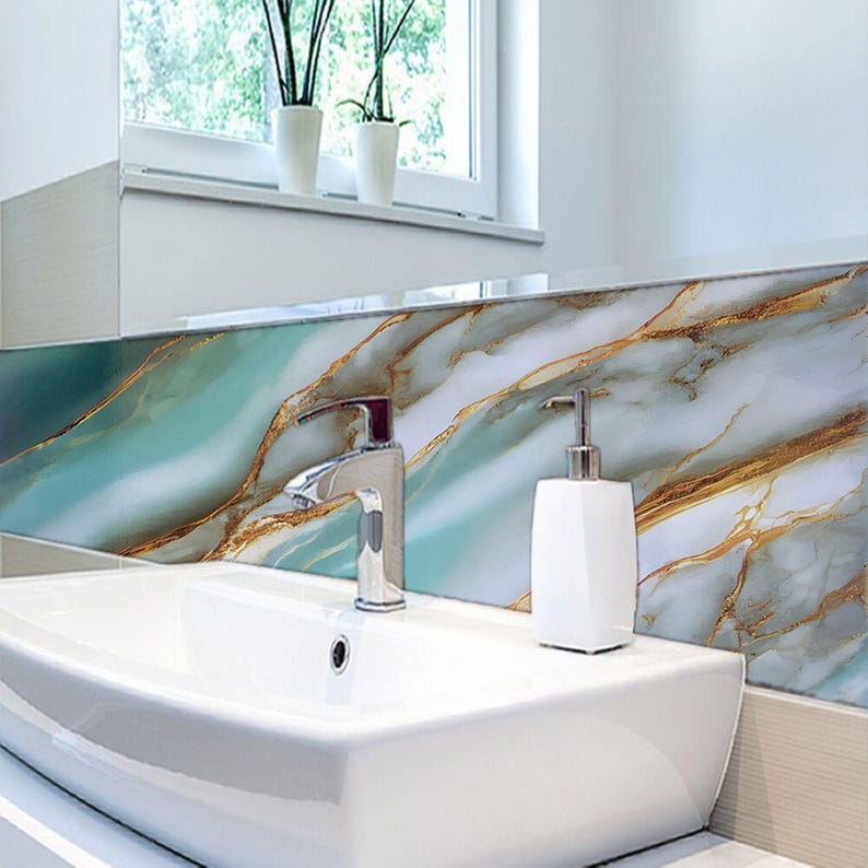 Peut inclure: Un lavabo en porcelaine blanche avec un robinet chrom&eacute; et un distributeur de savon blanc. Le lavabo est plac&eacute; devant un dosseret en marbre de couleur bleu-vert et or.