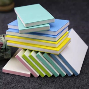 May include: A stack of colourful rectangular rubbers with white edges. The rubbers are arranged in a graduated pattern, with the largest rubber on the bottom and the smallest rubber on top. The rubbers are made of a soft, pliable material and are ideal for erasing pencil marks.