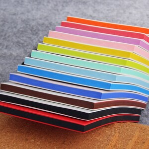 May include: A stack of colorful nail files with black and white stripes. The files are arranged in a rainbow pattern, with red at the bottom and orange at the top.