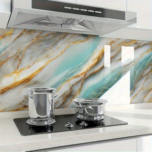 Peut inclure: Une cuisini&egrave;re &eacute;lectrique noire avec deux casseroles argent&eacute;es dessus. La cuisini&egrave;re est devant un dosseret de cuisine avec un motif de marbre dans des tons de bleu, blanc et or.