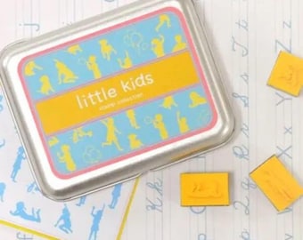 May include: A silver metal tin with a blue and yellow design featuring children playing. The tin contains a set of rubber stamps with images of children playing. The text "little kids stamp collection" is printed on the tin.