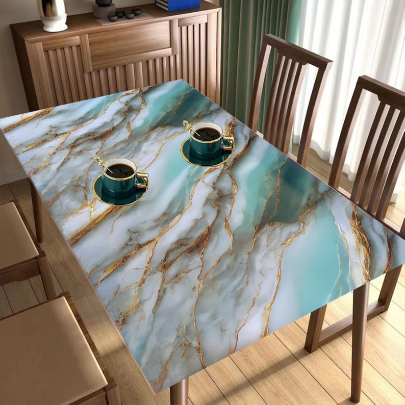 Peut inclure: Une nappe de table &agrave; motif marbr&eacute; avec des accents dor&eacute;s. La nappe est pos&eacute;e sur une table en bois avec deux tasses de caf&eacute; sur des soucoupes.