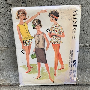 May include: Vintage McCall's sewing pattern for pre-teen sports separates. The pattern includes a top, skirt, pants, or shorts. The pattern number is 6287 and the size is 13/14. The bust size is 31 inches.