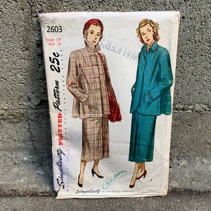 May include: Vintage Simplicity sewing pattern number 2603 for a two-piece outfit. The pattern is printed on white paper with a red and black border. The pattern includes a jacket and skirt. The jacket has a plaid pattern and the skirt is solid blue. The pattern is priced at 25 cents.