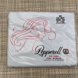 May include: A white Pepperell Red Label fine muslin flat sheet for a double bed, packaged in clear plastic. The packaging features a red line drawing of a person's profile and text stating One Flat Sheet Double Bed 81 x 108, 100% Cotton.