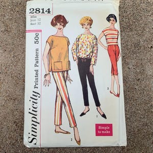 May include: A vintage Simplicity sewing pattern, number 2814, with illustrations of three outfits. The pattern includes a top with pockets, striped trousers, a patterned blouse, and capri trousers. The text "Simple to make" is also visible.