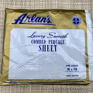 May include: A packaged white sheet with the text "Arlan's Luxury Smooth Combed Percale Sheet." The package is gold with blue text and a blue logo. The sheet measures 81 x 108 inches and is made of 100% cotton.