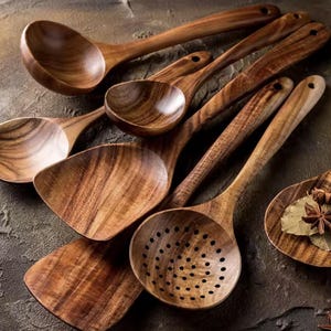 Peut inclure: Un ensemble d'ustensiles de cuisine en bois comprenant une grande louche, une cuillère à trous, une spatule plate et plusieurs cuillères à mélanger. Chaque pièce présente un grain de bois brun distinct, une finition lisse et un trou au manche.
