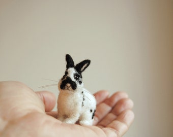May include: A small, black and white needle felted rabbit with black eyes and whiskers.