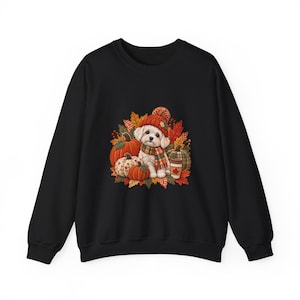 May include: A black crewneck sweatshirt featuring a graphic print of a white puppy wearing a red knit hat and a plaid scarf, surrounded by orange and patterned pumpkins, autumn leaves, and a coffee cup with a maple leaf design.
