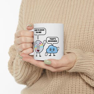 May include: A white ceramic mug featuring a cartoon graphic of a compact disc and a blue cloud. The disc has a speech bubble saying I USED TO HOLD 700 MB! and the cloud has a speech bubble saying THAT'S ADORABLE. The mug has a smooth finish.