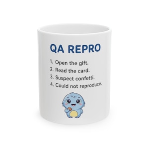May include: A white ceramic mug featuring the blue text QA REPRO followed by a numbered list: 1. Open the gift. 2. Read the card. 3. Suspect confetti. 4. Could not reproduce. Below the text is a small, light blue cartoon monster holding a cookie.