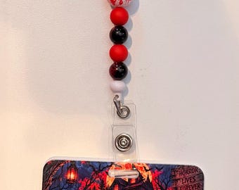Könnte beinhalten: Ein Ausweishalter mit rechteckigem Kartenhalter und einem Aufsatz, beide verziert mit Horrorfilmfiguren und dem Text "SPOOKY SEASON". Das Verbindungsband ist mit roten, schwarzen und weißen Perlen geschmückt, darunter eine Perle mit dem Wort "HELP".