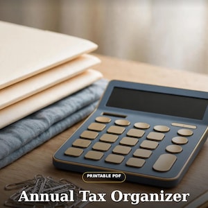 May include: A dark blue calculator with gold-coloured buttons sits next to a stack of light-coloured folders and a pile of silver paper clips. The text reads MoneyBlueprints, PRINTABLE PDF, Annual Tax Organizer, and Tax season, handled.