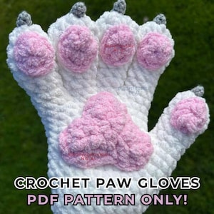 Puede incluir: Un guante de pata tejido a ganchillo en color blanco con cuatro pequeñas almohadillas circulares rosas en los dedos, una almohadilla central grande en forma de corazón rosa y pequeñas garras grises en las puntas. El texto CROCHET PAW GLOVES PDF PATTERN ONLY aparece.