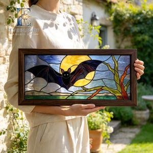 May include: A rectangular stained glass panel in a dark wood frame featuring a black bat flying in front of a large yellow full moon. The scene includes a dark blue sky with clouds and a tree with green and brown branches in the foreground.