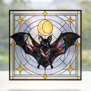 May include: A square stained glass panel featuring a central bat with iridescent black and purple wings. Above the bat is a yellow crescent moon. The background consists of clear textured glass circles and gold star accents in the corners.