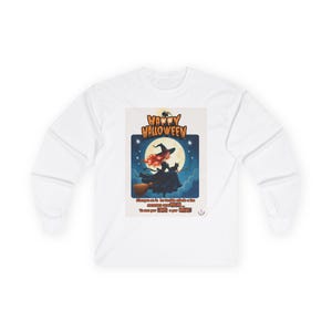May include: A white long-sleeve shirt featuring a graphic print of a witch with red hair riding a broomstick against a full moon. The text reads HAPPY HALLOWEEN and includes Spanish text below the illustration, with a small spider at the top.