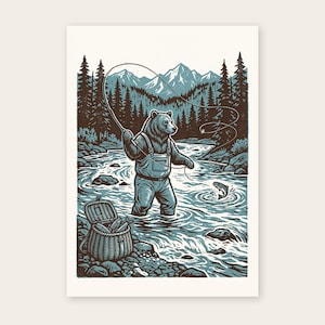 May include: A print featuring a bear wearing overalls and standing in a river whilst fly fishing. A fish jumps from the water near the bear, and a woven creel basket filled with fish sits on the rocky riverbank. The scene includes pine trees and mountains.
