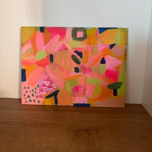 Op de afbeelding: Een rechthoekig schilderij op canvas met een abstracte compositie van levendige kleuren, waaronder neonroze, feloranje, limoengroen en diep marineblauw. Het kunstwerk toont gelaagde penseelstreken, geometrische vormen en kleine gestippelde patronen.