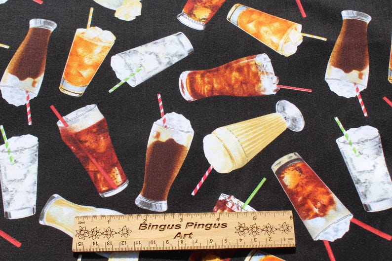 May include: Black fabric featuring a pattern of refreshing drinks, such as iced tea, fizzy drinks, and milkshakes. The drinks are in glasses and bottles, with straws. A wooden ruler is at the bottom.