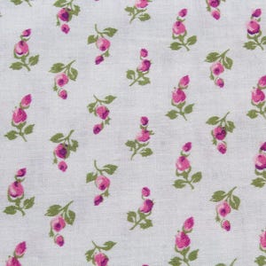 May include: A close-up of white fabric adorned with a repeating pattern of pink rose buds and green leaves. The floral design is evenly distributed, creating a delicate and feminine aesthetic. The material appears to be cotton or a similar lightweight fabric.