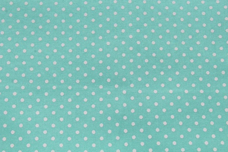 May include: A turquoise fabric with a white polka dot pattern.
