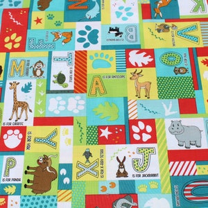 May include: A colorful fabric with a repeating pattern of letters, animals, and paw prints. Each letter is paired with an animal and the phrase "is for" followed by the animal's name. For example, "A is for Antelope".