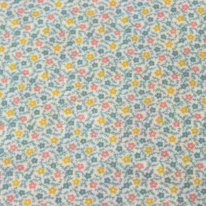 May include: A close-up of a fabric with a repeating floral pattern. The design features small pink and yellow flowers with green stems and leaves on a pale blue background. The fabric has a delicate, textured appearance.