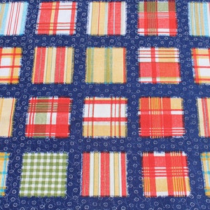 Peut inclure: Gros plan sur un tissu avec un motif répétitif de carrés. Chaque carré présente un motif à carreaux ou à rayures différent en rouge, jaune, vert et bleu. Le fond est bleu foncé avec un petit motif floral blanc.