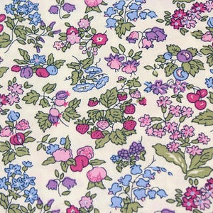 May include: A cream-colored fabric featuring a dense, repeating botanical print of small pink, purple, and blue flowers, green leaves, and clusters of red strawberries and cherries scattered across the surface in a detailed, colorful pattern.