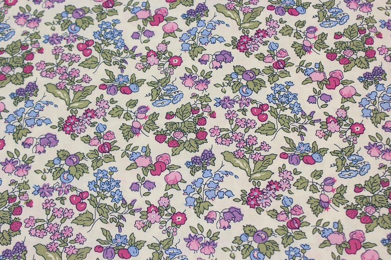 May include: A fabric featuring a dense floral and fruit pattern on a cream background. The design includes small strawberries, cherries, and various clusters of blue, purple, and pink flowers with green leaves distributed across the entire surface.