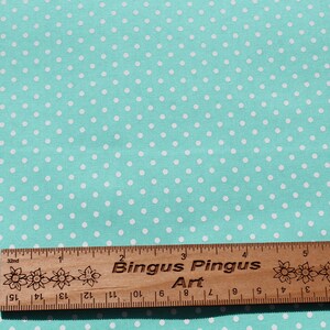 May include: A turquoise fabric with a white polka dot pattern. A wooden ruler with the text "Bingus Pingus Art" is placed on the fabric.