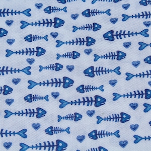 May include: A white fabric with a repeating pattern of blue fish skeletons and blue hearts.