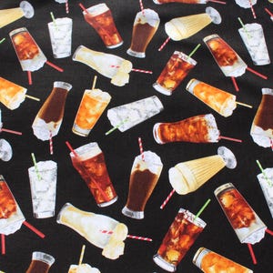 May include: Black fabric featuring a repeating pattern of cold drinks. The pattern includes iced tea, soda floats, and cocktails, each with a straw. The drinks are in clear, brown, and yellow colours.