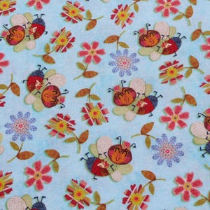 May include: A light blue fabric with a repeating pattern of cartoon bees, flowers, and leaves. The bees have red and blue bodies with smiling faces. The flowers are red, yellow, and blue.