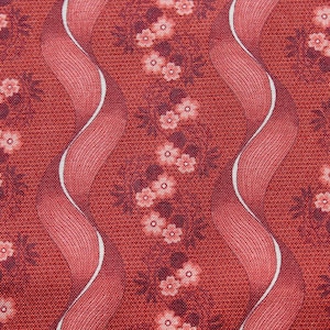May include: Close-up of a red fabric with a repeating floral pattern. The design features small, light pink flowers and dark red leaves. Wavy, ribbon-like stripes with white edges run vertically across the fabric.