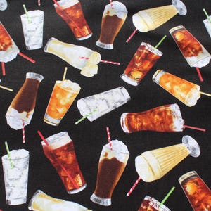 May include: Black fabric featuring a repeating pattern of various drinks, including cola, milkshakes, and iced beverages. The drinks are in different glasses and bottles, with straws and whipped cream. The colours include brown, white, and yellow.