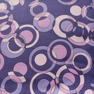 May include: Purple fabric with a repeating pattern of overlapping circles in shades of pink and purple.