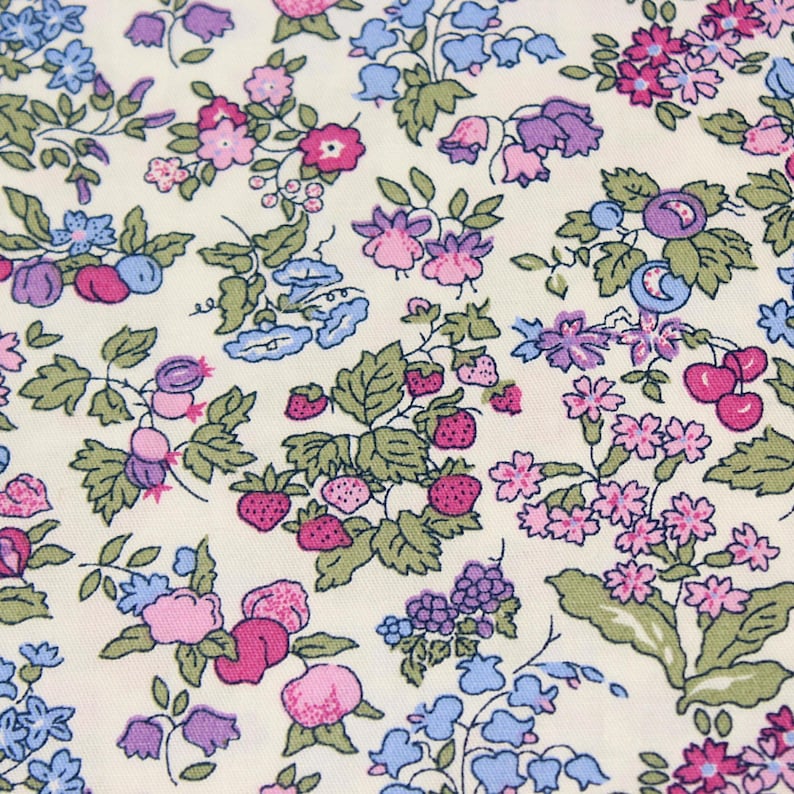 May include: A cream-colored fabric featuring a repeating pattern of small botanical illustrations including pink strawberries, purple grapes, blue bell-shaped flowers, and various small pink and blue blossoms with green leaves throughout the design.