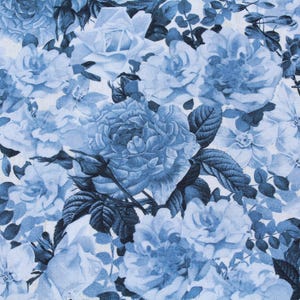 May include: A fabric with a repeating floral pattern. The design features various sizes of blue roses and other flowers with dark blue leaves against a white background. The overall effect is a classic, romantic style.