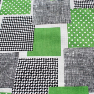 May include: A white fabric with a patchwork design featuring green, black, and white squares. The squares have different patterns, including polka dots, houndstooth, and a textured weave.