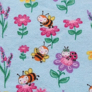 May include: A blue fabric with a repeating pattern of bees, ladybirds, and flowers. The flowers are pink, purple, yellow, and orange. The bees are yellow and black. The ladybirds are red with black spots.