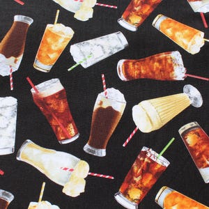 May include: Black fabric featuring a pattern of cold drinks, such as iced tea, cola, and milkshakes. The drinks are in various glasses and cups, with straws and whipped cream.