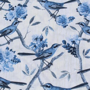 May include: A fabric with a repeating pattern of blue birds perched on branches with blue flowers and leaves against a white background. The birds have black beaks and are facing different directions.