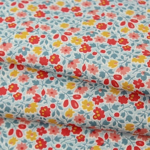 May include: Close-up of floral fabric with a light blue background. The fabric features a repeating pattern of small red, yellow, and pink flowers with green leaves. The fabric is folded, showing multiple layers.