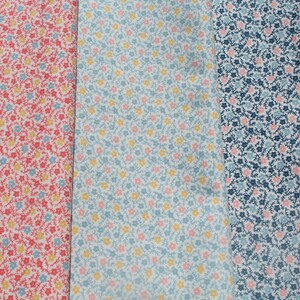 May include: Three fabric samples with floral designs. The first is red with yellow and blue flowers. The second is light blue with yellow and pink flowers. The third is navy blue with pink and light blue flowers.