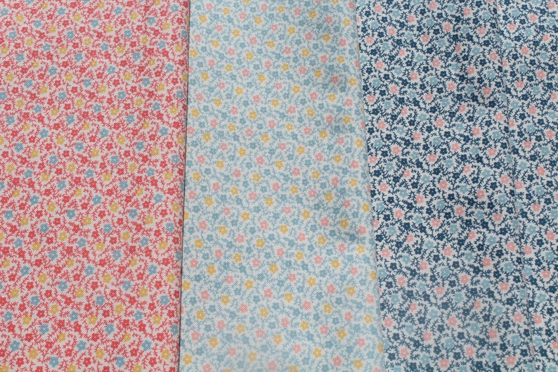 May include: Three fabric samples with floral designs. The first is red with yellow and blue flowers. The second is light blue with yellow and pink flowers. The third is navy blue with pink and light blue flowers.